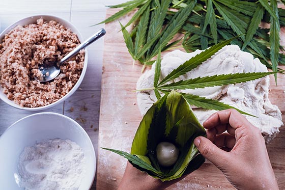 Cannabis leaves in background. Edibles being prepared for consumption in a leaf.