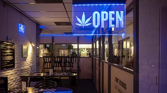 Cannabis cafe with neon OPEN sign.