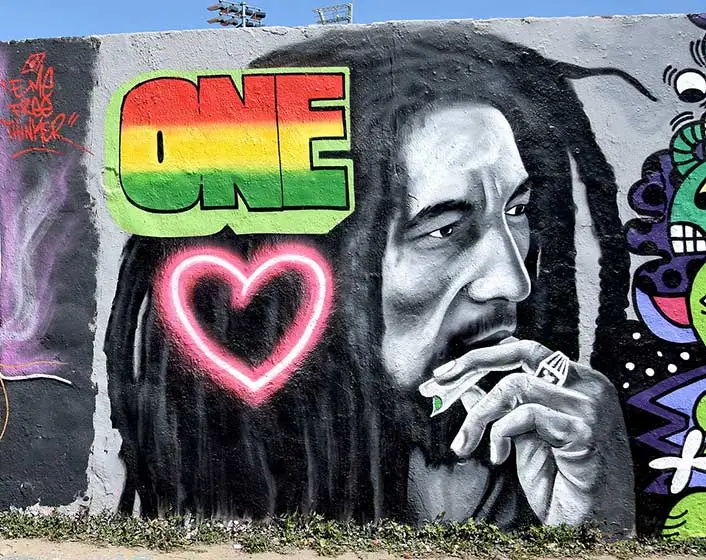 Bob Marley mural on a wall, with 'One Love' emblem on the image of his face